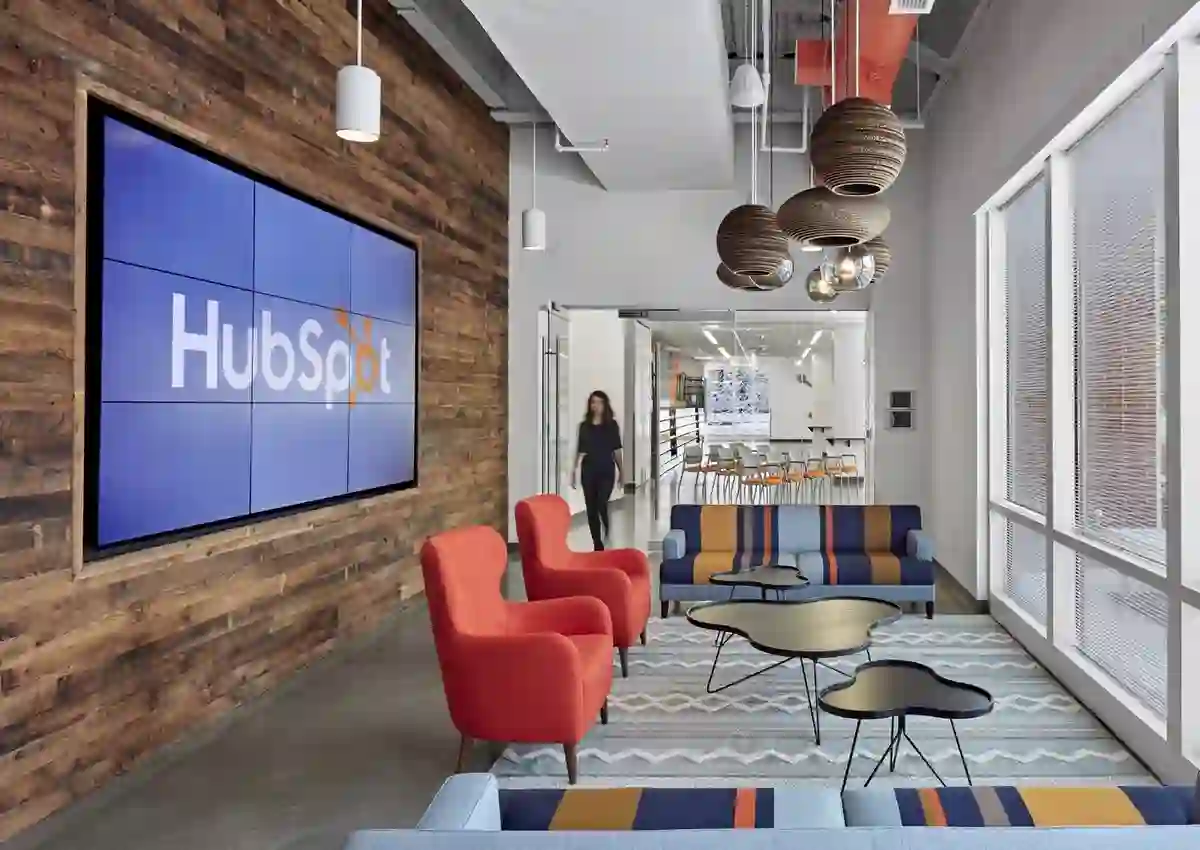 Oficinas de HubSpot con una pantalla de video mostrando el logo de la empresa, sillones y mobiliario de diseño en un espacio de trabajo abierto