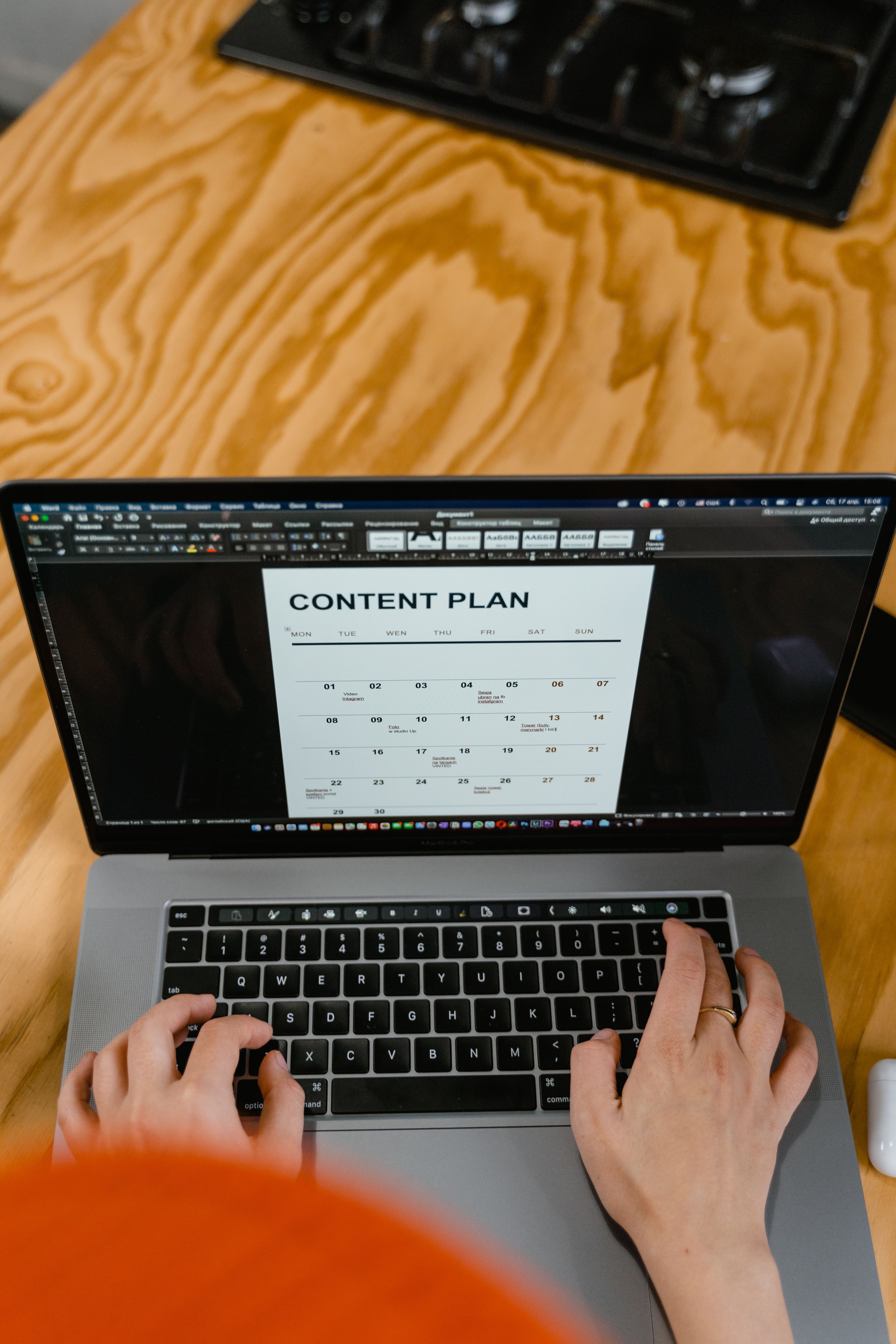 Persona trabajando en una laptop sobre un calendario editorial de contenidos lleno de publicaciones programadas